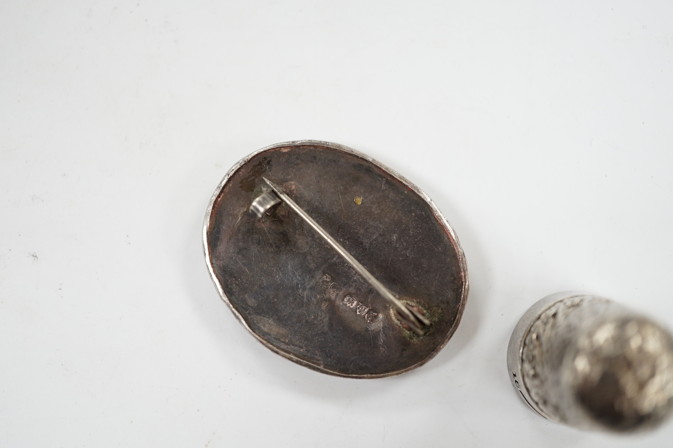 A George V silver thimble, a later silver brooch, a white metal, marcasite and black onyx brooch and one other brooch.